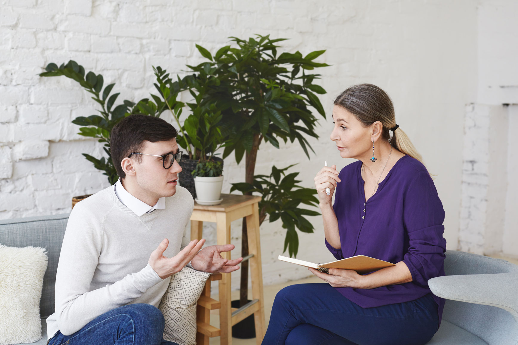 Psychology therapy psychiatry mental health counseling concept candid shot nervous self conscious young male glasses telling middle aged female